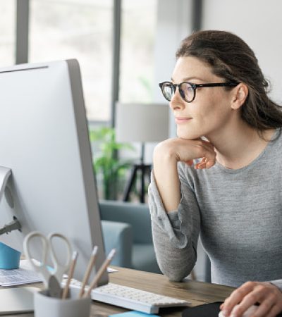 Professional woman sitting at desk and connecting with her computer, she is working from home